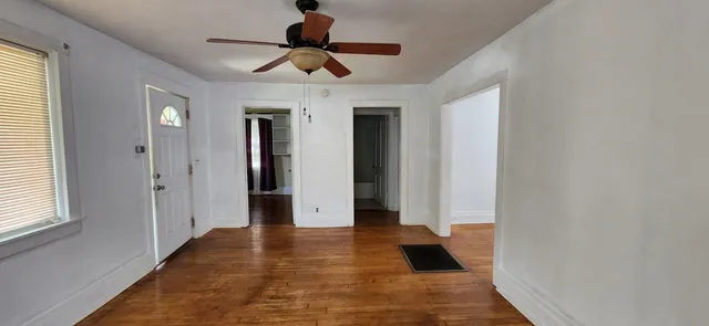 a view of an empty room with wooden floor and a window