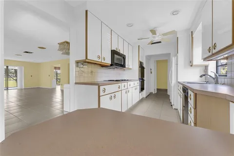 a open kitchen with stainless steel appliances granite countertop a refrigerator a stove and a sink with wooden floor