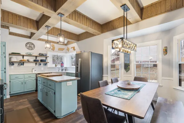 a kitchen with stainless steel appliances kitchen island granite countertop a table chairs and a chandelier