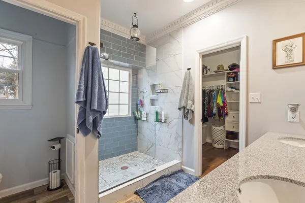 a bathroom with a granite countertop sink a mirror and shower