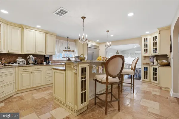 a dining room filled chandelier and kitchen view