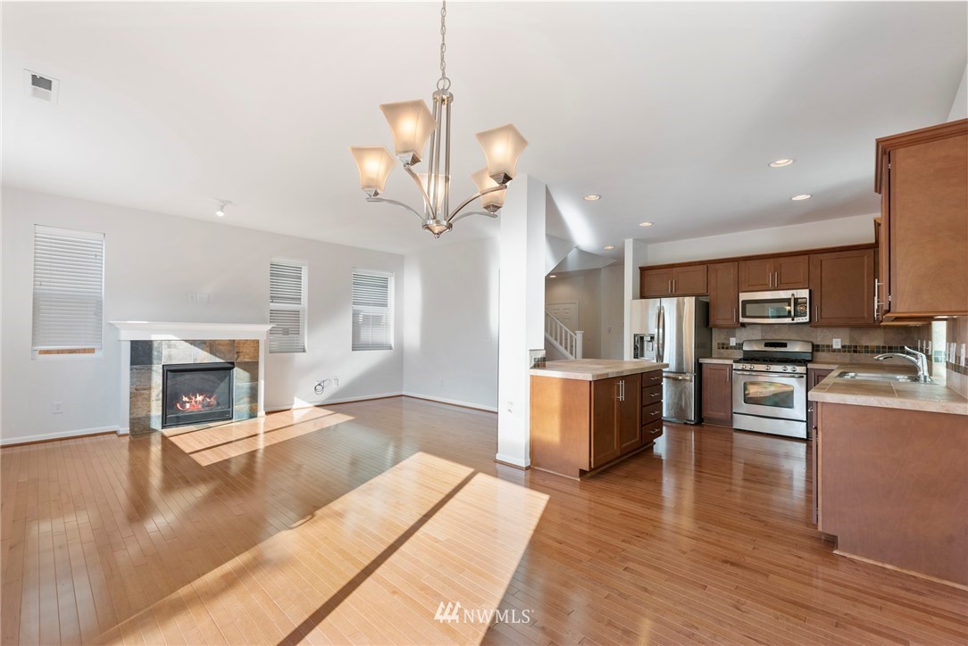 3910 177th Street Southeast Bothell, WA 98012 - Photo 6 of 27 a living room with stainless steel appliances kitchen island a flat screen tv and a fireplace
