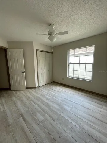 an empty room with wooden floor cabinet and windows