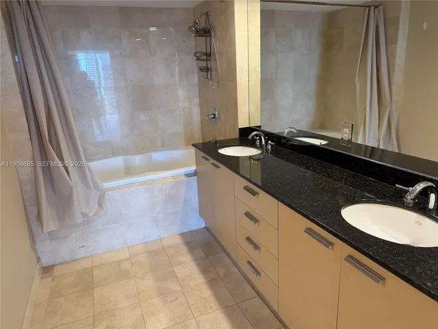 a bathroom with a granite countertop sink a mirror and a bathtub