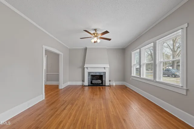a view of a livingroom with a fireplace a ceiling fan and windows
