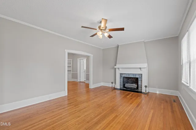 an empty room with wooden floor fireplace and windows