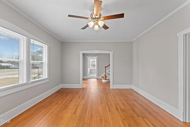 a view of empty room with wooden floor and fan