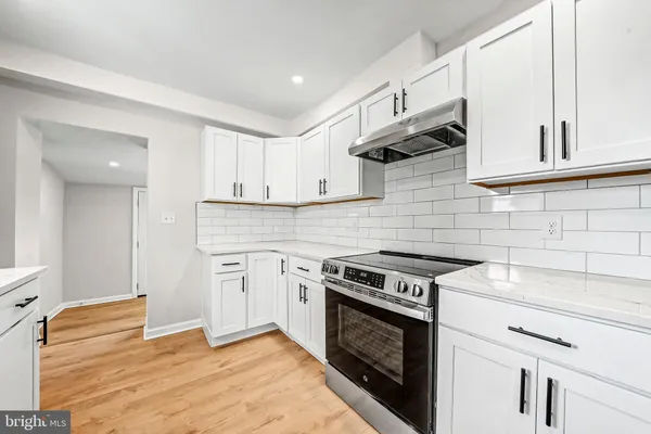 a kitchen with stainless steel appliances white cabinets and a stove top oven