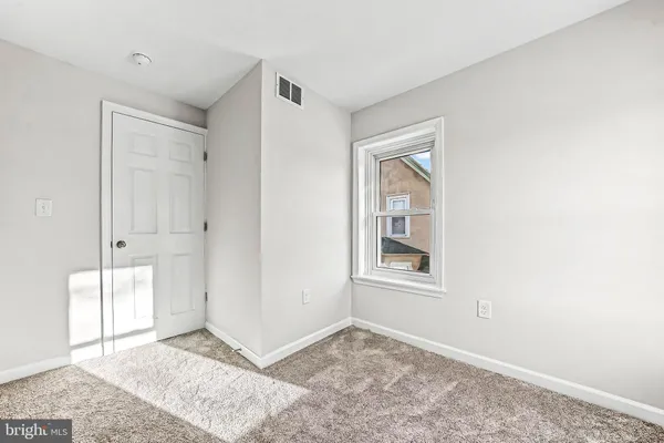 a view of an empty room with window and closet area