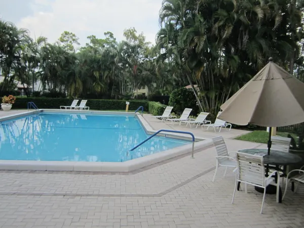 a view of a swimming pool with lawn chairs under an umbrella