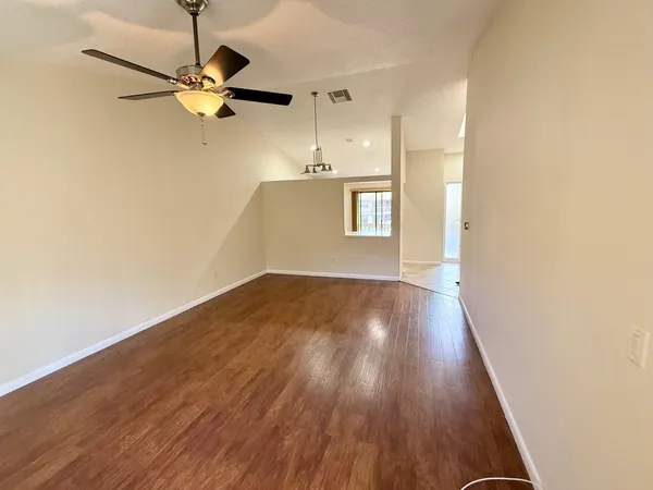 a view of a room with wooden floor a ceiling fan and a window