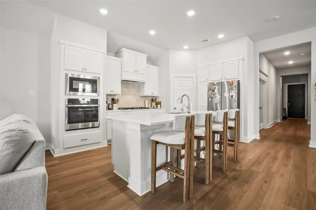 a kitchen with stainless steel appliances kitchen island granite countertop a refrigerator and a stove top oven