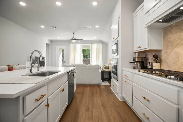 a large kitchen with kitchen island white cabinets and stainless steel appliances