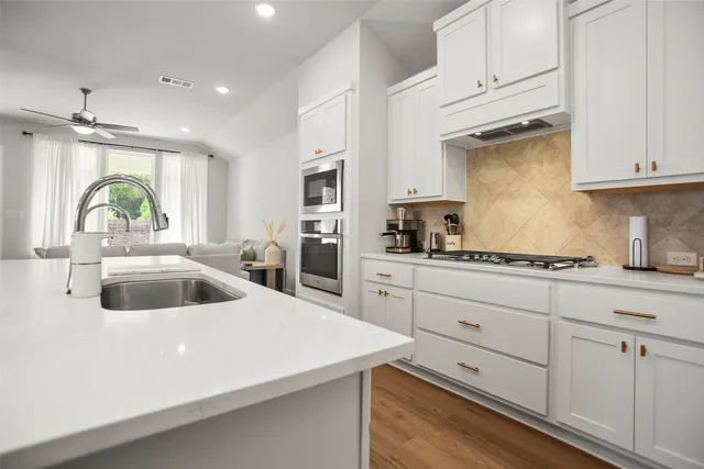a kitchen with cabinets appliances a sink and a counter space
