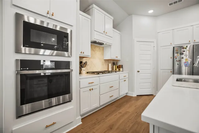 a kitchen with stainless steel appliances kitchen island granite countertop a stove a microwave and a refrigerator