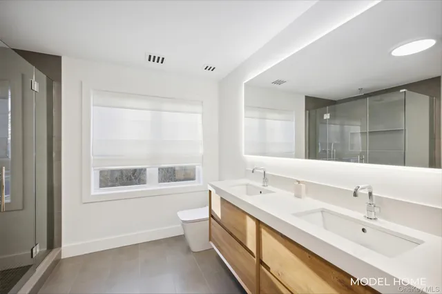 a bathroom with a double vanity sink a large mirror and a bathtub