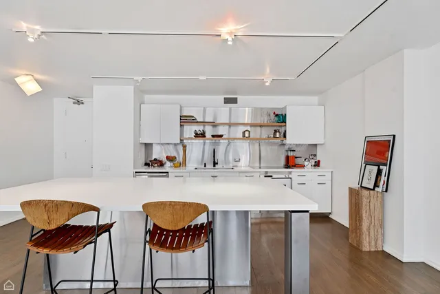 a very nice looking kitchen with a dining table chairs stove refrigerator and wooden floor