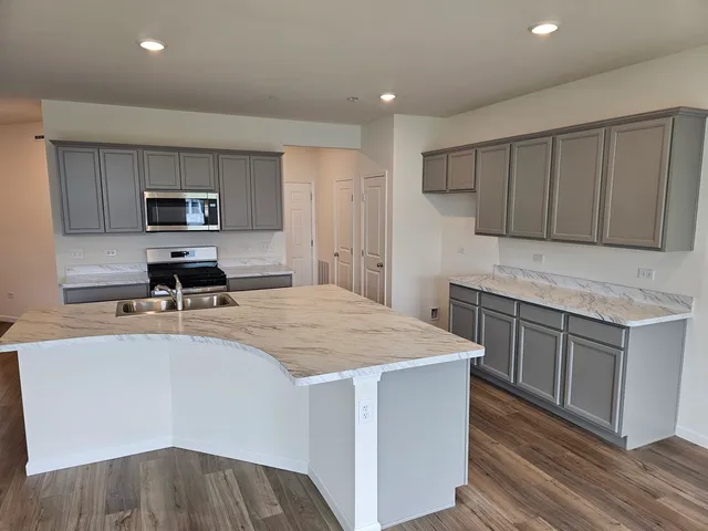 a kitchen with kitchen island a stove a sink and a refrigerator