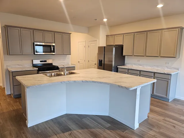 a kitchen with stainless steel appliances a refrigerator a sink a stove a microwave and wooden cabinets