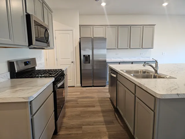 a kitchen with stainless steel appliances granite countertop a sink stove and refrigerator