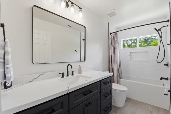 a bathroom with a double vanity sink toilet mirror and bathtub