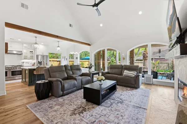 a living room with couches a coffee table and kitchen view with wooden floor