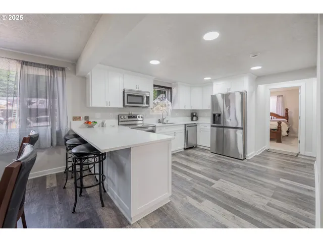 a open kitchen with kitchen island a stove a refrigerator a sink a dining table and chairs