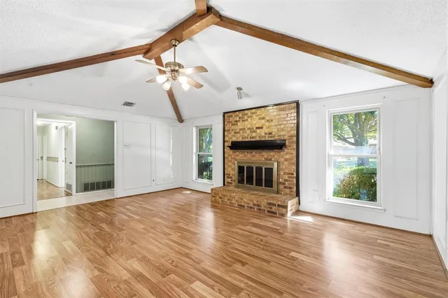 a view of empty room with fireplace and wooden floor