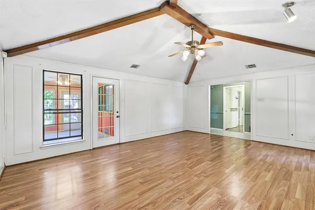 a view of an empty room with window and wooden floor