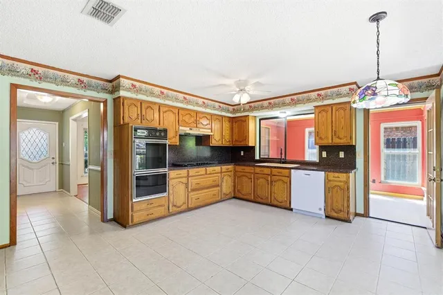 a large kitchen with stainless steel appliances kitchen island granite countertop a refrigerator and a sink