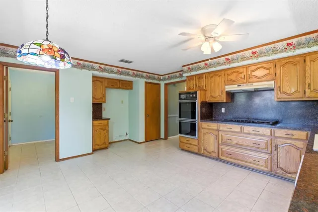 a kitchen with stainless steel appliances granite countertop a cabinets and a chandelier