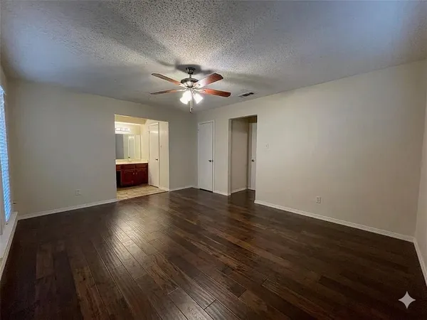 a view of an empty room with wooden floor and closet