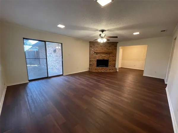 an empty room with wooden floor fireplace and windows
