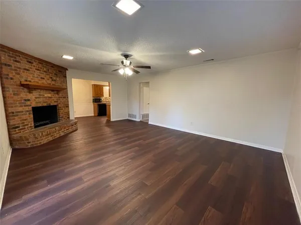an empty room with wooden floor fireplace and windows