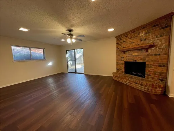 a view of an empty room with wooden floor and a fireplace
