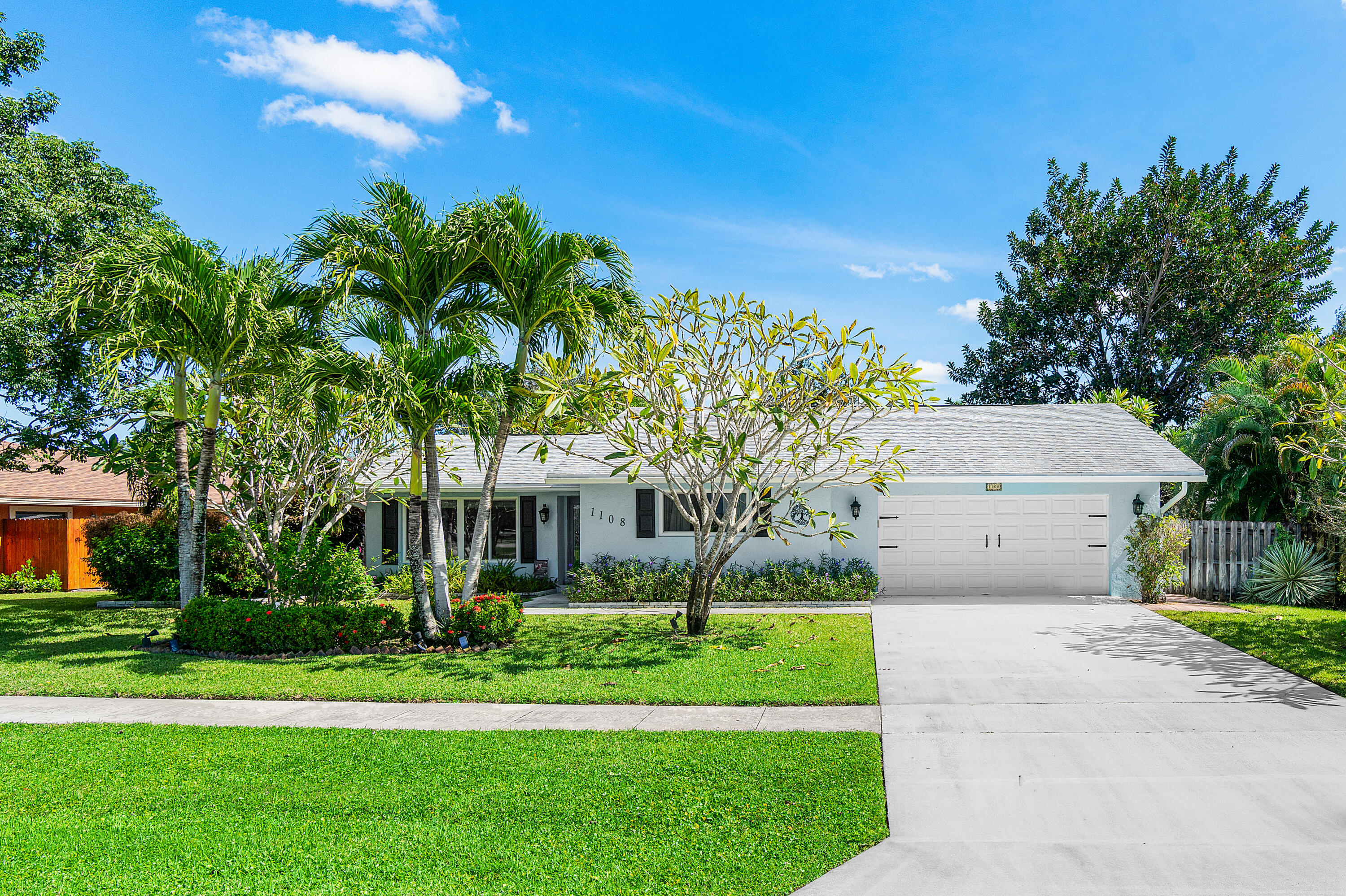1108 Petrel Road Wellington, FL 33414 - Photo 1 of 46 a front view of a house with a garden and trees