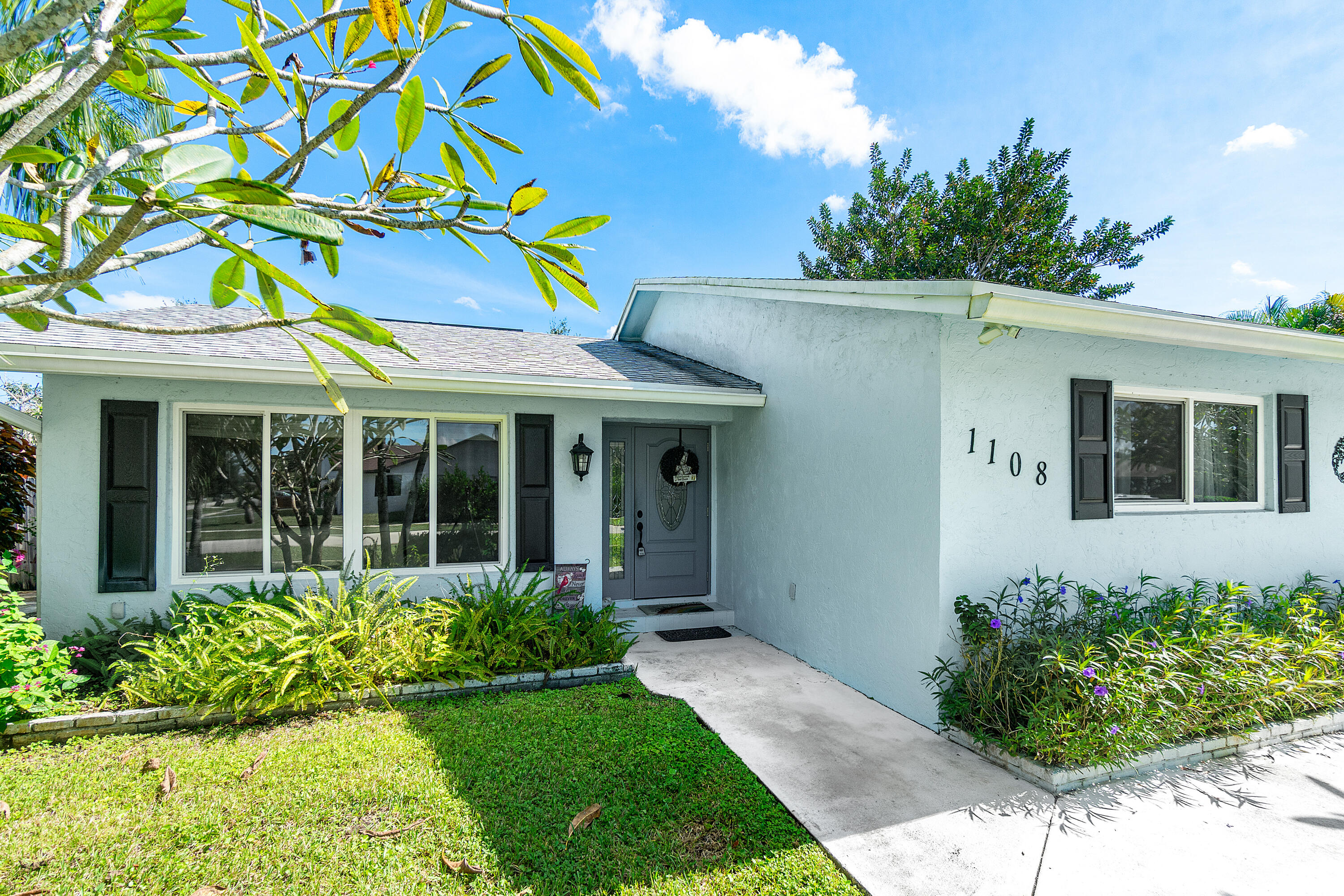 1108 Petrel Road Wellington, FL 33414 - Photo 4 of 46 a view of a house with potted plants and a yard
