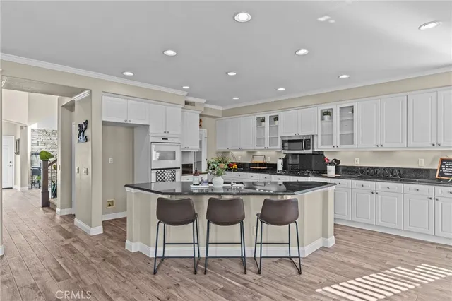 a kitchen with stainless steel appliances granite countertop a table chairs sink refrigerator and cabinets