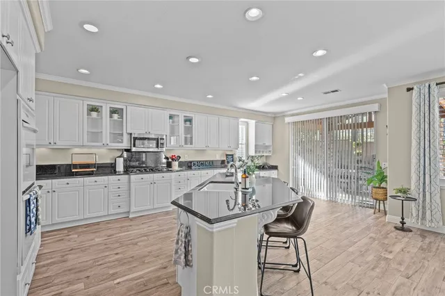 a kitchen with stainless steel appliances granite countertop a stove top oven a sink dishwasher a dining table and chairs with wooden floor