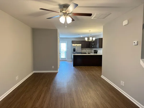 a view of kitchen and empty room with wooden floor