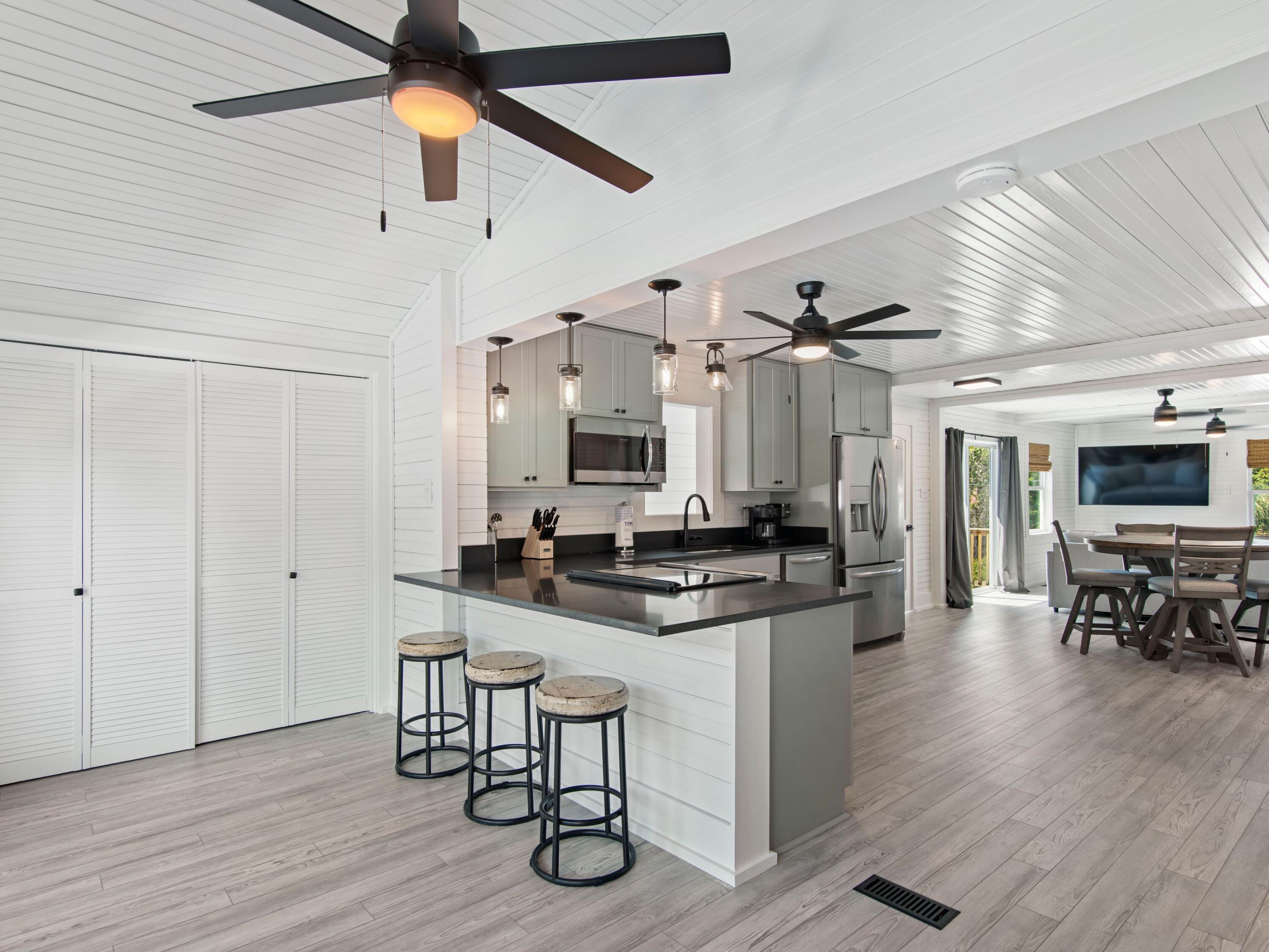 89 Tarpon Street Destin, FL 32541 - Photo 45 of 53 a kitchen with stainless steel appliances kitchen island granite countertop a stove top oven a sink a dining table and chairs with wooden floor