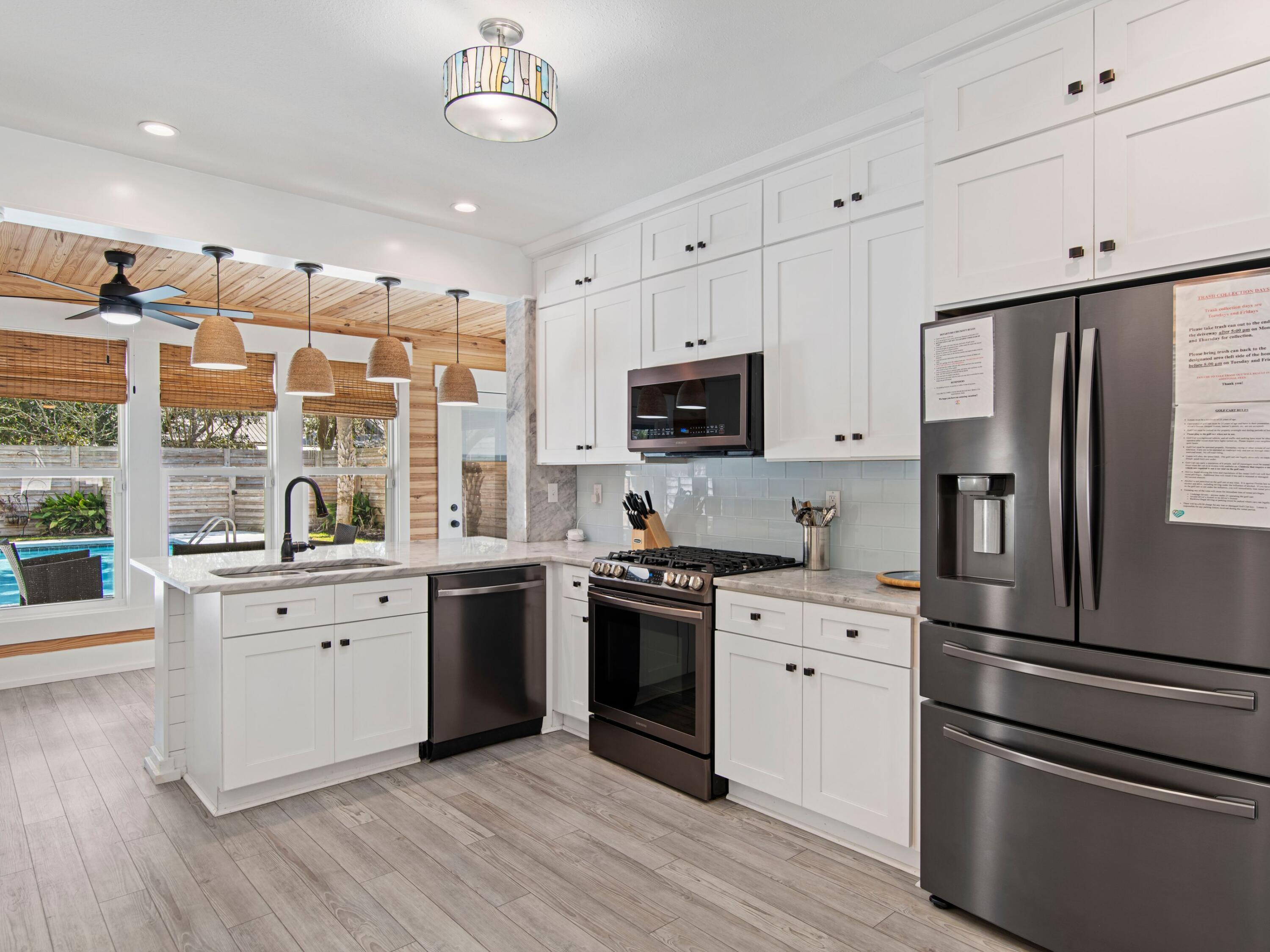 89 Tarpon Street Destin, FL 32541 - Photo 5 of 53 a kitchen with white cabinets stainless steel appliances and wooden floor