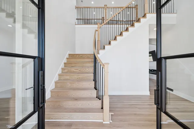 a kitchen with stainless steel appliances granite countertop a refrigerator a sink dishwasher and white cabinets with wooden floor