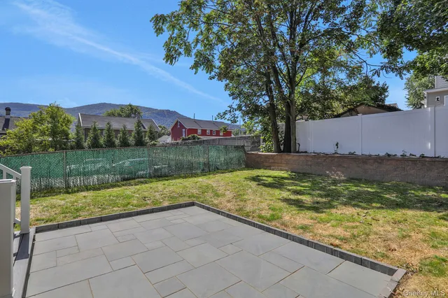a view of house with backyard and trees in the background