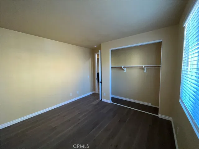 an empty room with wooden floor closet and windows