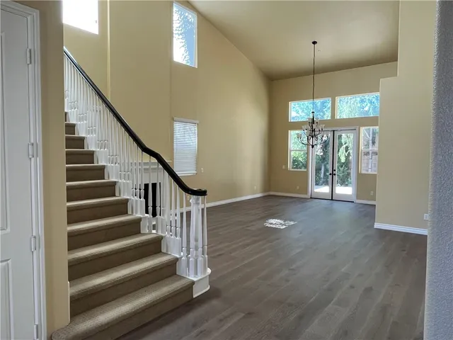 a view of an empty room with wooden floor and fan