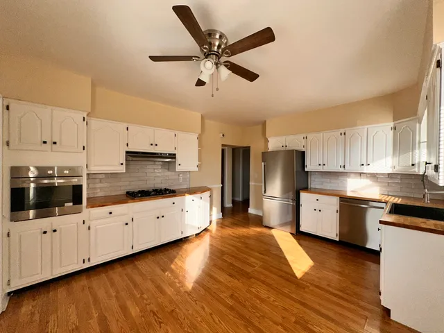 a large kitchen with cabinets wooden floor and stainless steel appliances