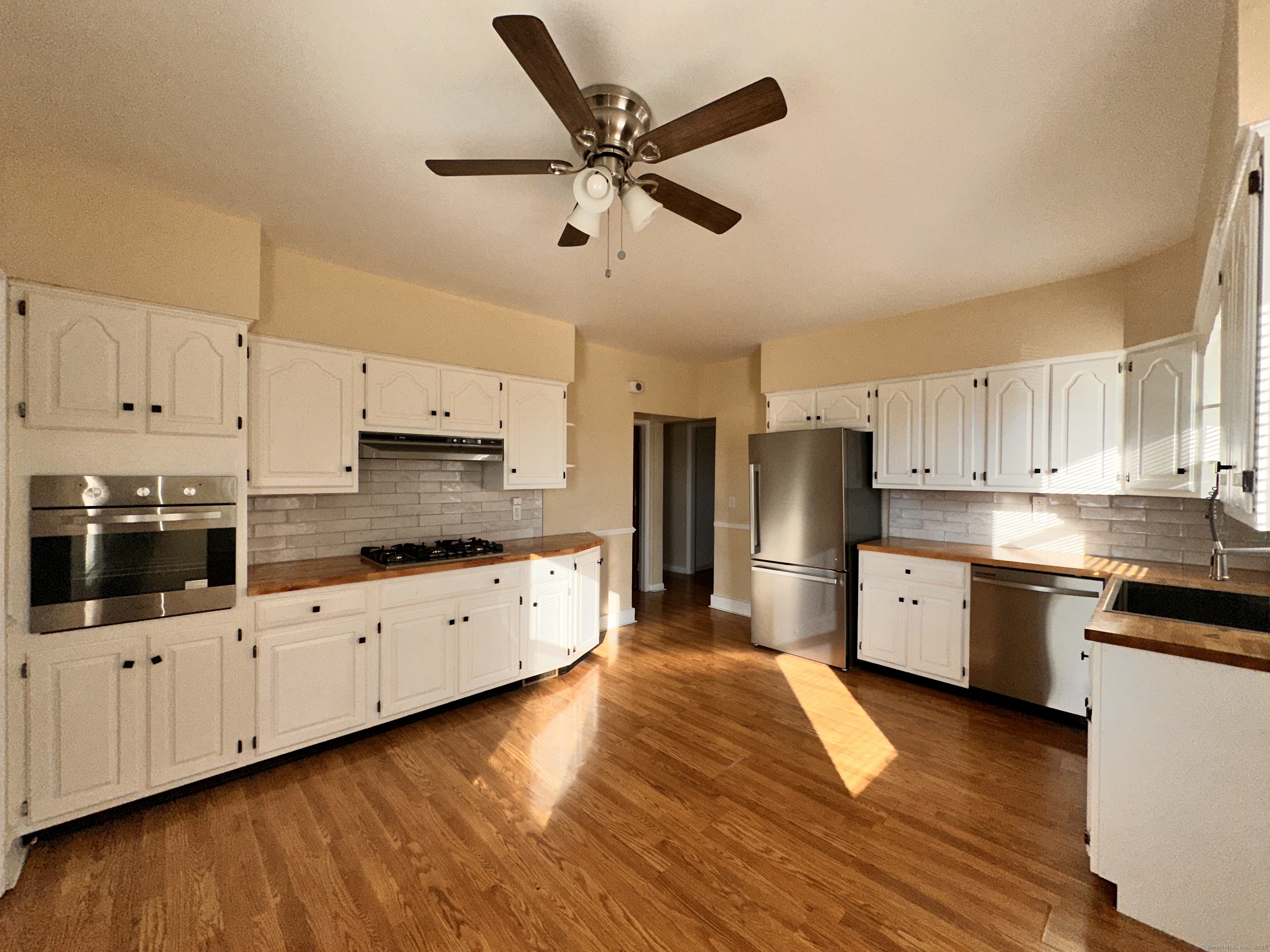 a large kitchen with cabinets wooden floor and stainless steel appliances