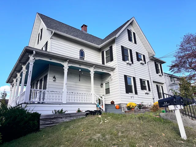 a view of a white house with large windows and a yard