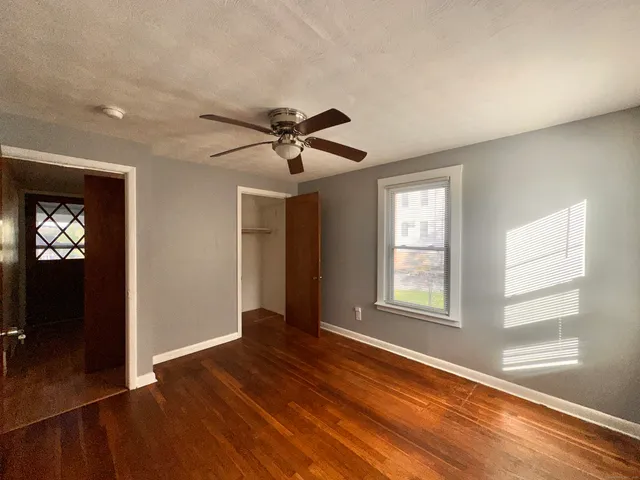 a view of an empty room with wooden floor and a window